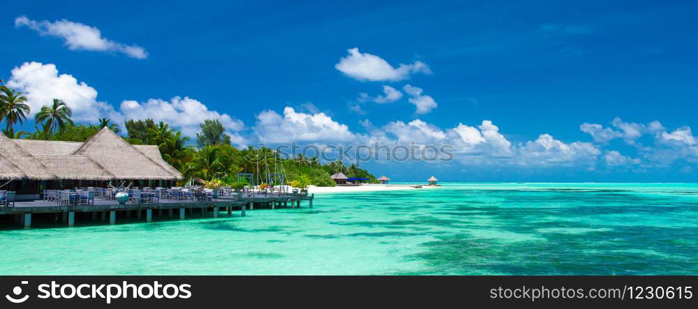 Beach with white sand, turquoise ocean water and blue sky with clouds in sunny day. Natural background for summer vacation. Panoramic view.