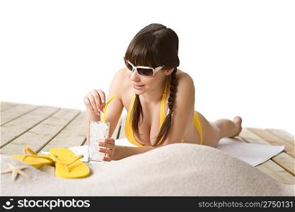 Beach - woman with cold drink in bikini sunbathing lying down on towel