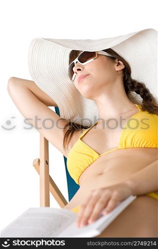 Beach - Young woman in bikini and hat relax with book sunbathing on deckchair