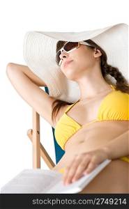 Beach - Young woman in bikini and hat relax with book sunbathing on deckchair
