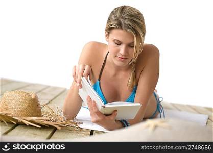 Beach - Young woman in bikini with book lying down sunbathing