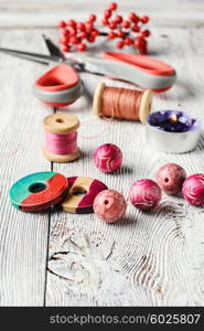 Beads and spools of thread for needlework on bright background. Accessories for home crafts