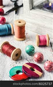 Beads and spools of thread for needlework on bright background. Beads and sewing thread