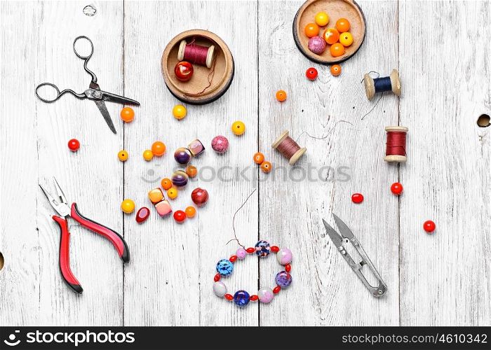 Beads for decoration. Round beads for bracelets and necklaces on white wooden background.View from the top