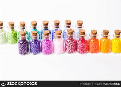 Beads in the vintage mini glass bottles with corks isolated on white. Colorful beads in the bottles