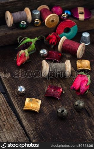 Beads,spools of thread on vintage wooden background