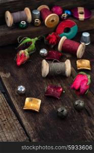 Beads,spools of thread on vintage wooden background