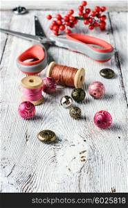 Beads,thread and scissors for needlework on a light grey wooden background