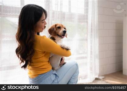 Beagle dog with her owner’s girl on a weekend getaway sitting and resting and looking out of the window in the living room of the house