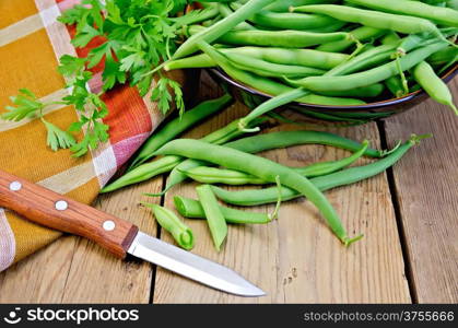 Beans asparagus green, checkered napkin, knife, parsley on a wooden boards background