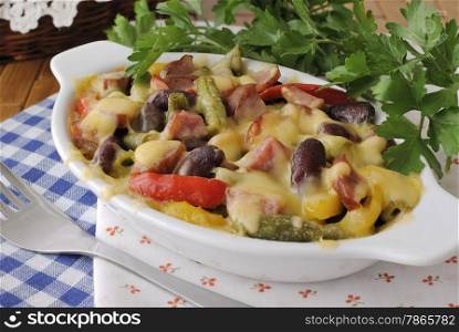 Beans with ham and vegetables, baked with cheese on the plate