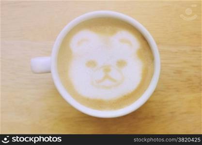 Bear latte art coffee cup on wooden table with retro filter effect