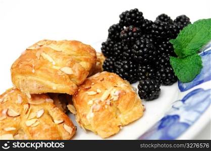 Bearclaw pastries with fresh picked blackberries on a blue and white plate with a mint leaf garnish. Bearclaws and Blackberries