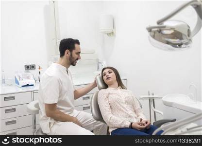 Bearded dentist male explaining procedure to a female patient