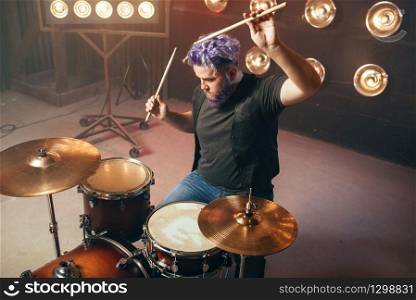 Bearded drummer with colorful hair on the stage with lights, vintage style. Musical performer, live music performing. Bearded drummer with colorful hair on the stage