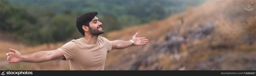 Bearded man breathing fresh air and open arms over natural background in the morning. Good health. Copy space.
