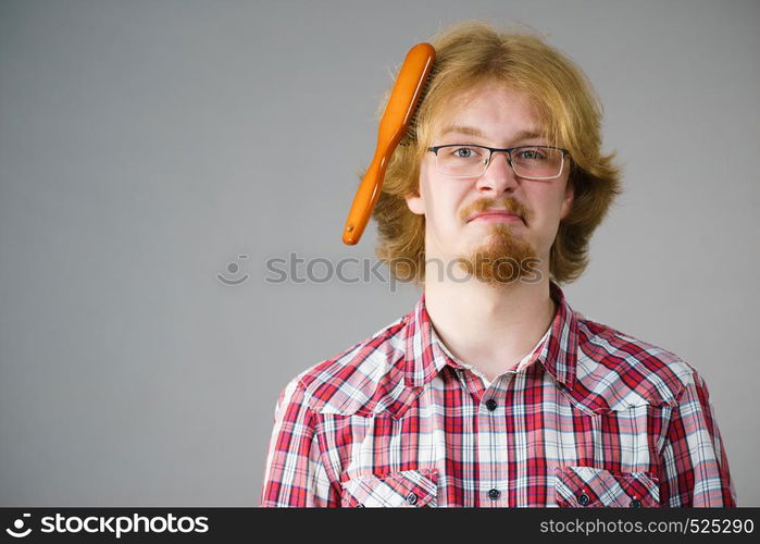 Bearded man having trouble with combing his hair using brush. Male haircare problems concept.. Man having problem with brushing hair