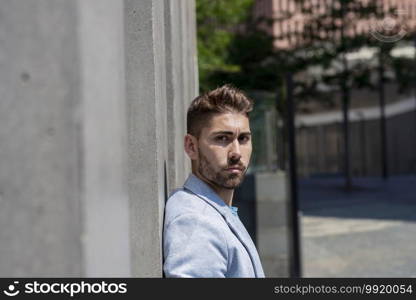 Bearded man leaning against wall and thinking