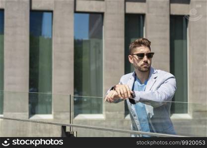 Bearded man leaning on a fence while looking away in the city