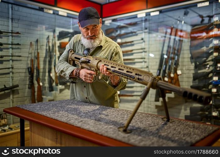 Bearded man reload powerful rifle in gun store. Weapon shop interior, ammo and ammunition assortment, firearms choice, shooting hobby and lifestyle, self protection. Bearded man reload powerful rifle in gun store