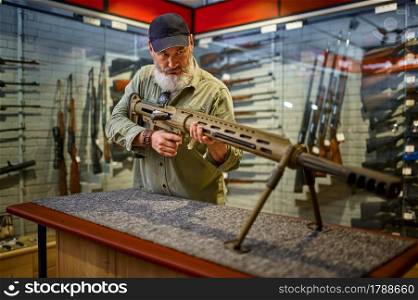 Bearded man reload powerful rifle in gun store. Weapon shop interior, ammo and ammunition assortment, firearms choice, shooting hobby and lifestyle, self protection. Bearded man reload powerful rifle in gun store