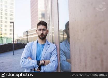 Bearded man with crossed arms, model of fashion, in urban background wearing casual clothes