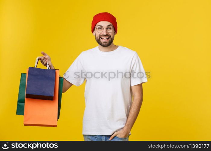 Bearded man with shopping bags with happy feeling isolated on yellow bacground.. Bearded man with shopping bags with happy feeling isolated on yellow bacground