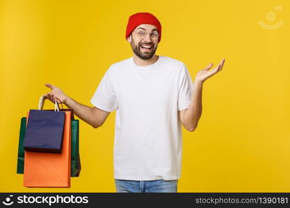 Bearded man with shopping bags with happy feeling isolated on yellow bacground.. Bearded man with shopping bags with happy feeling isolated on yellow bacground