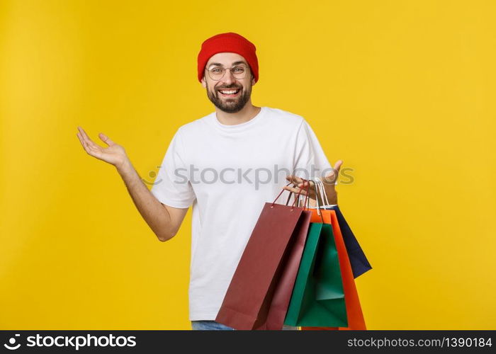 Bearded man with shopping bags with happy feeling isolated on yellow bacground.. Bearded man with shopping bags with happy feeling isolated on yellow bacground