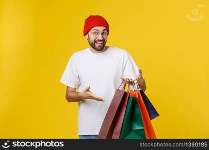 Bearded man with shopping bags with happy feeling isolated on yellow bacground.. Bearded man with shopping bags with happy feeling isolated on yellow bacground