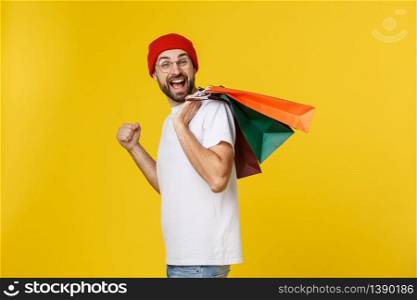 Bearded man with shopping bags with happy feeling isolated on yellow bacground.. Bearded man with shopping bags with happy feeling isolated on yellow bacground
