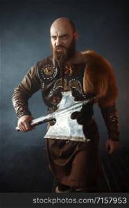 Bearded viking with axe enters the battle, barbarian image. Ancient warrior in smoke. Bearded viking with axe enters the battle