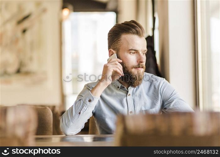 bearded young man talking cellphone restaurant
