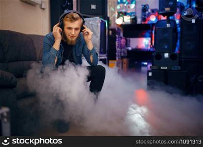 Bearded young musician choosing headphones in music store. Assortment in musical instrument shop, professional equipment for performers