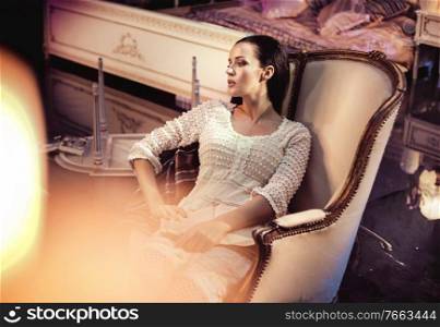 Beautfiul young woman resting in a luxurious, antique armchair