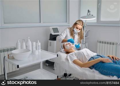 Beautician applying clay face mask on woman face side view. Rejuvenation treatment concept. Beautician applying clay face mask on woman face side view