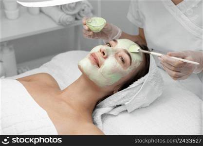 beautician applying face mask female client 4