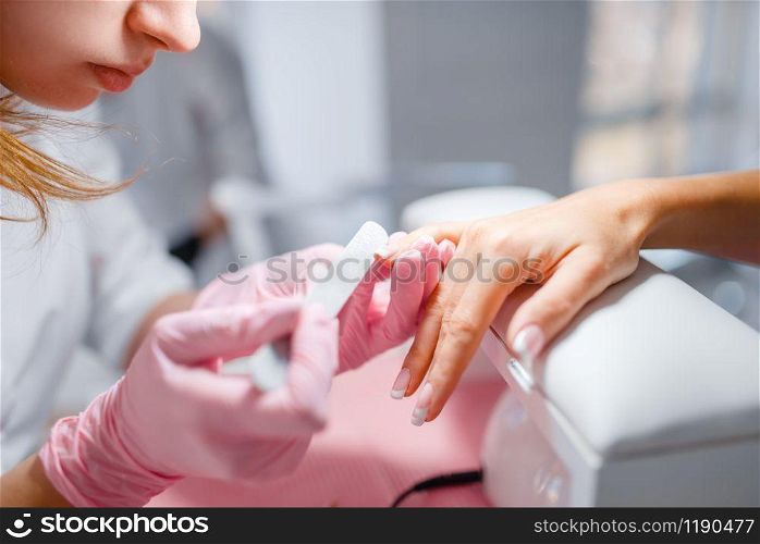 Beautician salon, manicure, nails polishing. Hands care treatment for female client in beauty shop, woman at the cosmetologist, master works with fingernails
