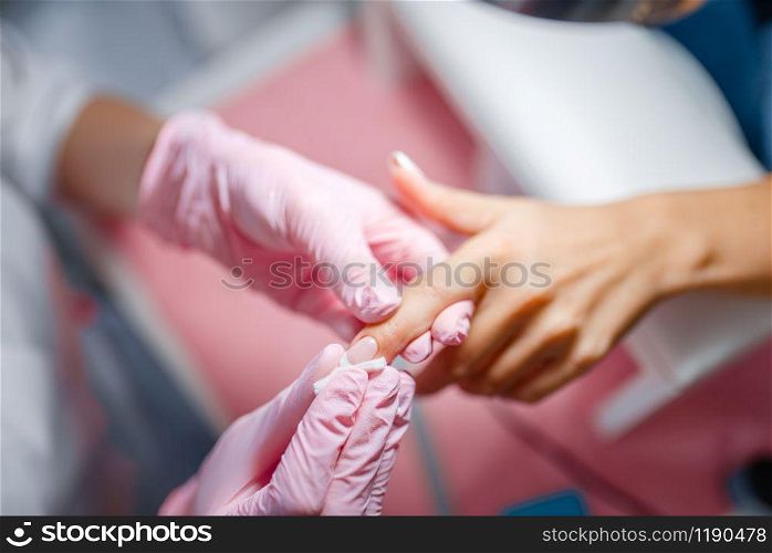Beautician salon, manicure, nails polishing. Hands care treatment for female client in beauty shop, woman at the cosmetologist, master works with fingernails. Beautician salon, manicure, fingernails polishing