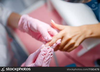 Beautician salon, manicure, nails polishing. Hands care treatment for female client in beauty shop, woman at the cosmetologist, master works with fingernails. Beautician salon, manicure, fingernails polishing