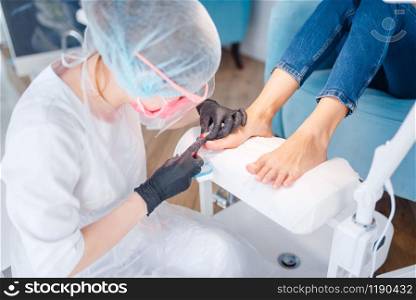 Beautician salon, pedicure, cuticle removal procedure. Nail care treatment for female client in beauty shop, doctor in gloves works with customer toenails. Beautician salon, pedicure, cuticle removal