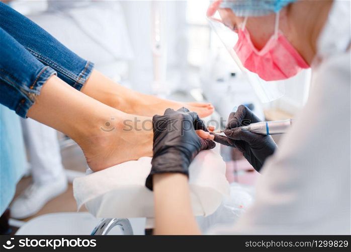 Beautician salon, pedicure, polish procedure. Nail care treatment for female client in beauty shop, doctor in gloves works with customer toenails. Beautician salon, pedicure, polish procedure
