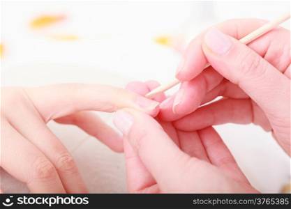 Beautician with cosmetic stick cleaning cuticles hands of female client. Manicure and skincare. Woman in beauty spa salon.