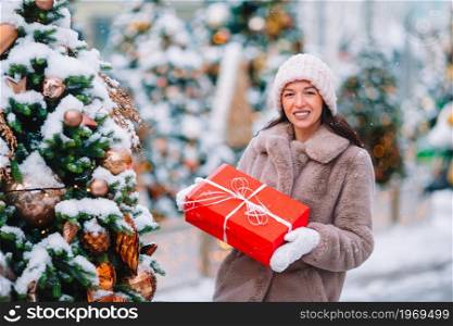 Beautidul woman near Christmas tree in the snow outdoors. Happy girl near fir-tree branch in snow for new year.