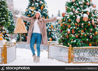 Beautidul woman near Christmas tree in the snow outdoors. Happy girl near fir-tree branch in snow for new year.