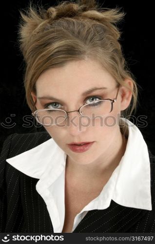 Beautiful 25 year old woman in suit over black. Wearing eyeglasses.