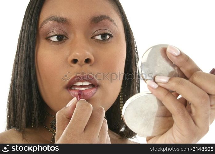 Beautiful 27 year old African American woman putting on lipgloss in small mirror.