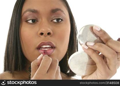 Beautiful 27 year old African American woman putting on lipgloss in small mirror.