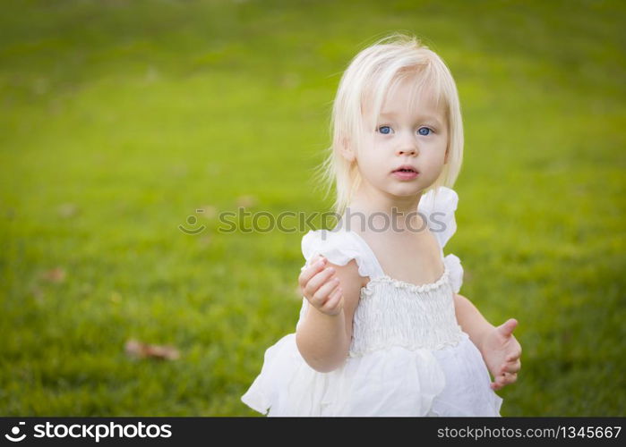 Beautiful Adorable Little Girl Wearing White Dress In A Grass Field.