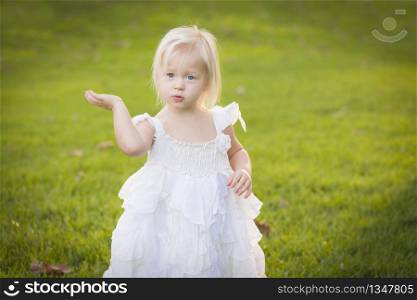 Beautiful Adorable Little Girl Wearing White Dress In A Grass Field.